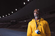 © Wavebreak Media - African american senior male coach standing on the running track at night