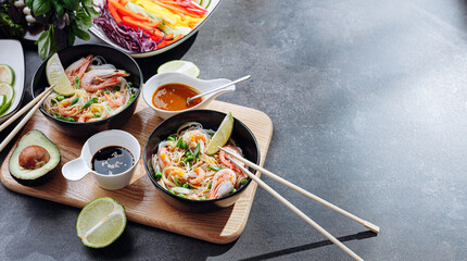 Wall Mural - romantic dinner for two. Asian cuisine, rice noodles with shrimp and seafood, green peas and onions. soy sauce and various fresh vegetables. romantic dinner in black plates with Japanese chopsticks