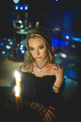 Poster - Elegant female in a black dress looking at illuminated candles