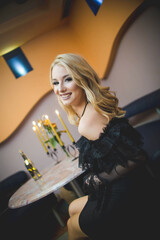 Poster - Happy attractive female sitting in a restaurant and posing