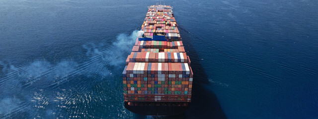 Aerial drone ultra wide photo above huge colourful container carrier vessel cruising deep blue open ocean sea