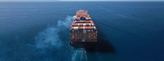 aerial drone ultra wide photo above huge colourful container carrier vessel cruising deep blue open 