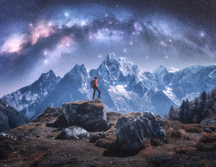 Wall Mural - arched milky way and sporty woman on the stone and mountains in snow at night. girl with backpack, s