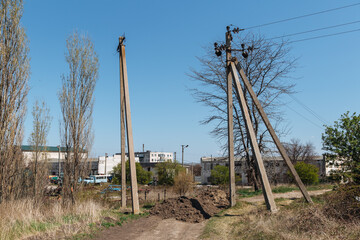 A concrete support for a power line against the background of a summer cottage village.