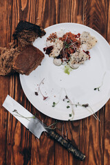 Wall Mural - Plate with delicious tartare, toasted bread and salad on a wooden table. Healthy gourmet French food made of raw meat.