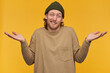 © timtimphoto - Portrait of doubtful, confused male with blond hair and beard. Wearing green beanie and beige sweater. Shrugs with hands lifted and wry face. Watching at the camera isolated over yellow background