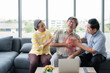 © Apiwan - Senior Asian man sitting on couch and using hand touching to chest from having heart attack in living room with elderly friends to help and take care.