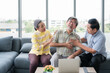 © Apiwan - Senior Asian man sitting on couch and using hand touching to chest from having heart attack in living room with elderly friends to help and take care.