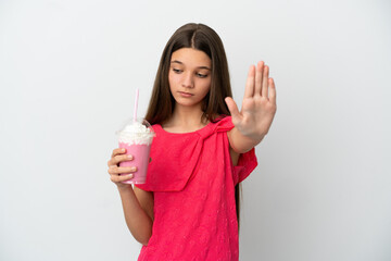 Wall Mural - Little girl with strawberry milkshake over isolated white background making stop gesture and disappointed