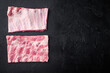 Fresh rack of raw pork spare ribs, on black stone background, top view flat lay, with copy space for text