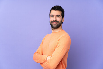 Wall Mural - Caucasian handsome man over isolated purple background with arms crossed and looking forward
