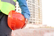 Worker holding red protective helmet at construction site