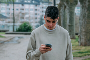 Wall Mural - young male teenager on the street looking at the mobile phone