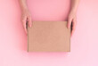 Delivery woman hold parcel box with copy space on pink background, mockup or template of cardboard box