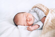 © nataliaderiabina - Newborn sleep at first days of life. Portrait of new born baby one week old in crib in cloth background.