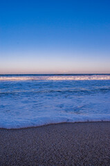 Vertical shot of the beach under a clear sky at sunset