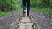 Hiker Walking On Boards Along The Trail To Stay Off The Muddy Path - Low Angle Waist Down Follow View