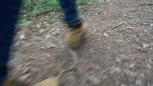 A Hiker Quickly Steps Along A Forest Trail - Low Angle With Legs And Boots Only Visible