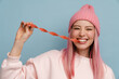 © Drobot Dean - Young white woman with pink hair smiling and eating strip candy