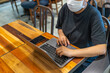 © Quang - Woman wearing protective mask and using laptop at cafeteria