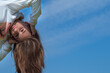 Girl upside down on a background of blue sky. Emotions.
