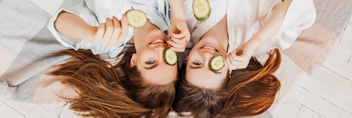 Wall Mural - two girls make homemade face and hair beauty masks. cucumbers for the freshness of the skin around t