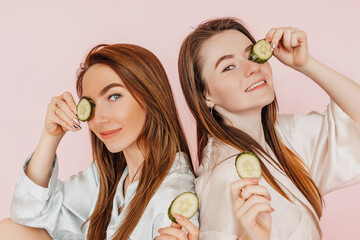 Wall Mural - two girls make homemade face beauty masks. cucumbers for the freshness of the skin around the eyes. 