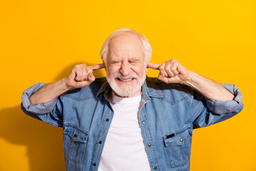 Photo of unhappy irritated upset old man close ears fingers bad mood loud noise isolated on yellow color background