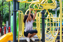 Happy Mixed Race Family In Park. Adorable Child Girl Kid Playing And Hanging On Jungle Gym At Children Playground. Little Daughter Enjoy And Having Fun Outdoor Lifestyle Weekend Activity In Summer.