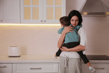 Wall Mural - Depressed single mother with child in kitchen, space for text