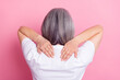 Back view photo portrait of senior woman touching shoulders got backache isolated on pastel pink color background