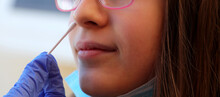 caucasian girl in the clinic makes a swab in the nose to look for coronavirus