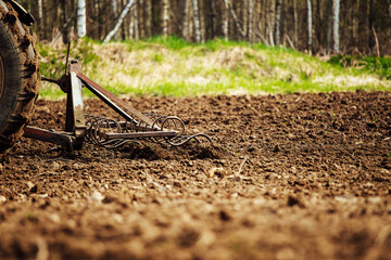 Wall Mural - plow tractor plows the land for planting agricultural plants. the farmer cultivates the land in the spring for sowing seeds. iron plow of the mechanized machine