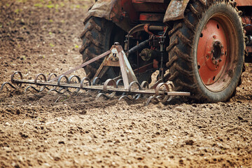 Wall Mural - plow tractor plows the land for planting agricultural plants. the farmer cultivates the land in the spring for sowing seeds. iron plow of the mechanized machine