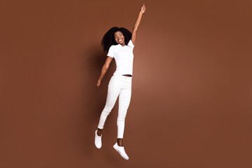 Poster - Full length portrait of cheerful carefree dark skin girl raise arm hold imagine umbrella isolated on brown color background