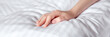 Beautiful female hand on white linens in the rays of the sun. Selective focus. Banner