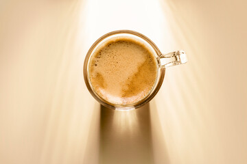 Wall Mural - coffee cup with cream coffee, top view on background with sunlight.