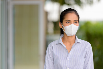 Wall Mural - Asian woman wearing face mask to protect from coronavirus Covid-19 while thinking