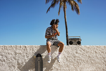 Young trendy african man enjoy music playlist in summer vaction in the city - Skater boy with retro boombox outdoor