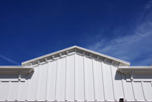 Roofline Of A White Wooden Building Under Deep Blue Sky With The Moon Visible