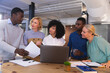 © Wavebreak Media - Team of diverse office colleagues discussing together over a laptop at modern office