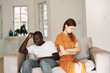 © SHOTPRIME STUDIO - offended African man and emotional woman sitting on the sofa family problems interior quarrel