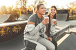 © BalanceFormCreative - Two best female friends sitting at the skate park and joying in coffee to go.