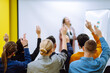 © maxbelchenko - Group of young people sitting at a conference together raised hands to express their views. Business group meeting seminar training concept. Planning, analysis, collaborate work in teamwork.