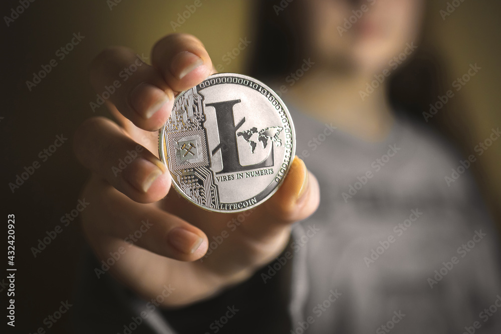 Young woman holding silver litecoin in her hand close-up view, advertising crypto coins, digital currency concept business background