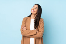 Young Caucasian Woman Isolated On Blue Background Looking Up While Smiling