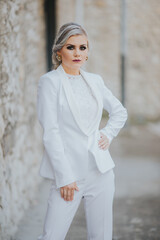 Poster - Elegant fashionable Caucasian female in a pretty white suit and pants posing for fashion photoshoot