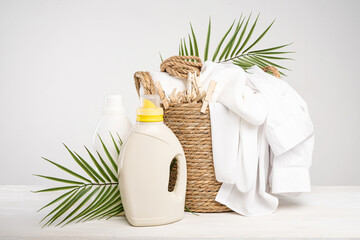 Wall Mural - Wicker basket with white linen, clothespins, clothesline, washing gel and fabric softener on a white table with palm branches. Mockup laundry day in a tropical hotel.