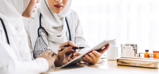 Wall Mural - Two muslim asian woman doctor working with clipboard and tablet computer on desk in hospital.healthcare and medicine