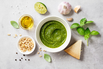 Wall Mural - Fresh Italian pesto sauce with basil, pine nuts, parmesan cheese and olive oil on the light gray background. Top view 